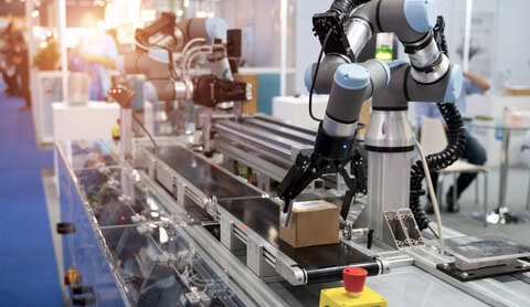 Universal Robots UR5 Collaborative Robot on a production line placing a small cardboard box onto a conveyor belt