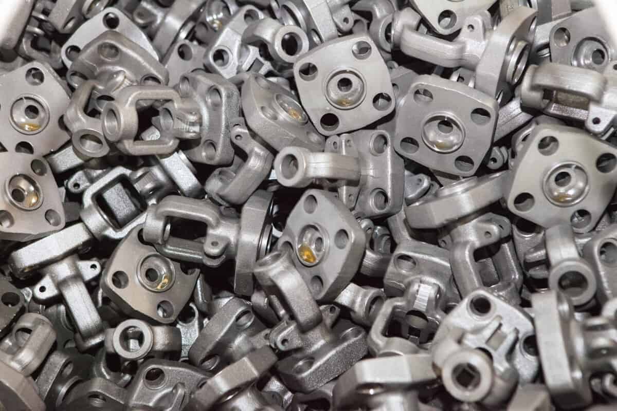 Close-up em ângulo alto de um grande monte de peças de aço laminado pesadas e em orientações aleatórias, demonstrando um desafio complexo para bin picking robótico e a necessidade de uma solução precisa de visão artificial com IA.