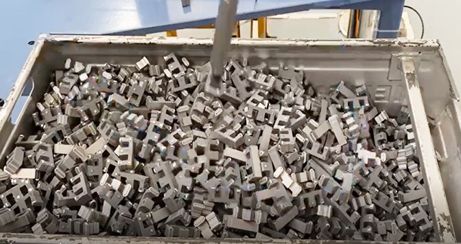 Robotic bin picking of randomly oriented steel switchgear parts from a metal bin in a manufacturing cell, showcasing industrial AI vision automation.
