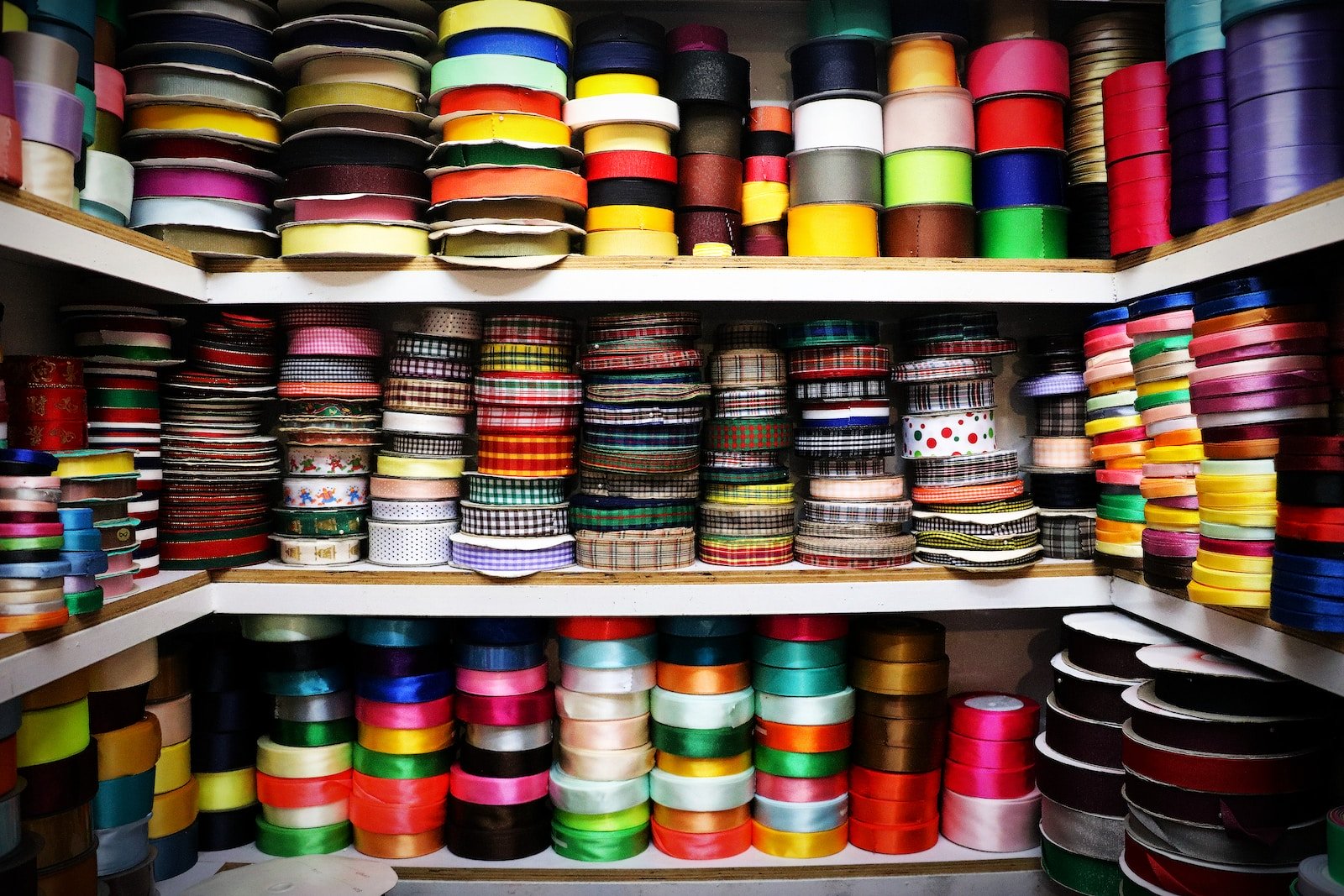 Shelves of ribbon materials with varied patterns, textures, and colors used in fabric quality inspection.