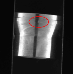 Close-up view of a precision machined component showing a localized surface defect highlighted with a circular detection marker.