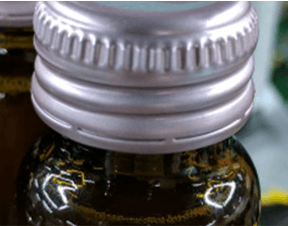 Example of missing printed batch or date code on aluminum bottle caps for OCR inspection reference.