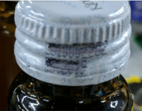 Example of smudged or partially unreadable characters on bottle cap printing used for OCR defect classification.
